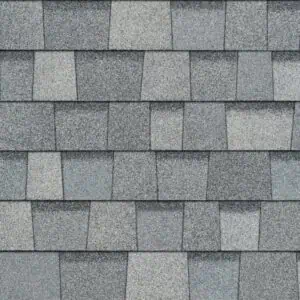 Close-up of a grey shingled roof texture showing an overlapping pattern of rectangular asphalt shingles with hail damage.