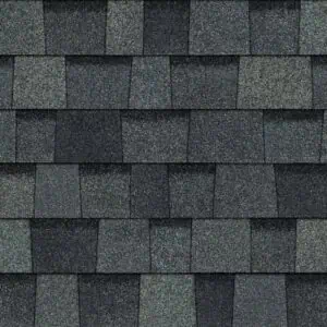 Pattern of overlapping grey roofing shingles in shades of dark and light grey, arranged in a staggered formation.
