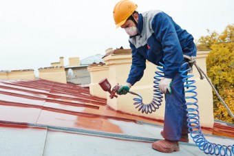 Expert applying coating to a metal roof.