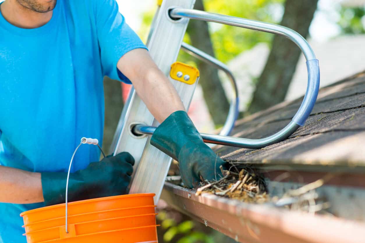 seasonal roof maintenance Austin - man cleaning gutters