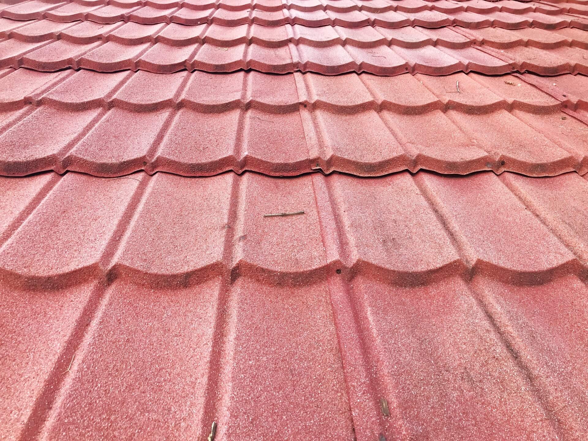 Stone-coated steel roof with interlocking tiles and minor debris