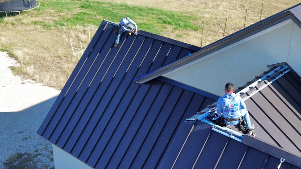 Leander contractors installing metal roof with safety harnesses.